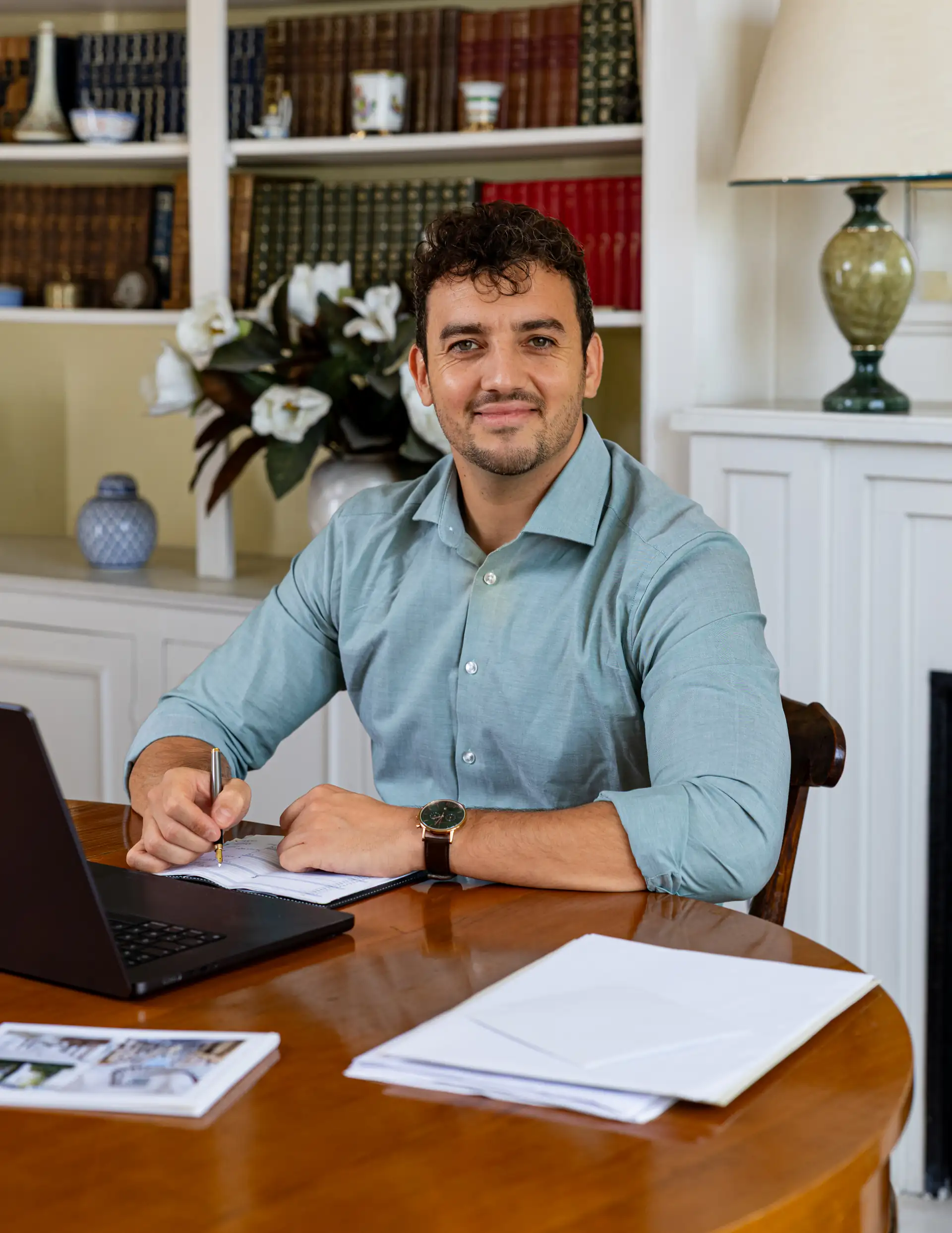 Théo Mével assis à un bureau, un stylo à la main, devant un ordinateur et des documents.