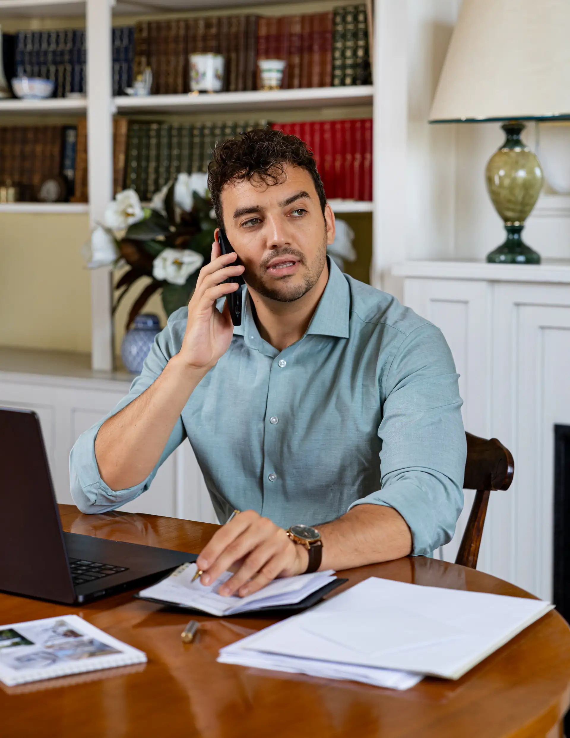 Théo Mével assis à un bureau, téléphone à l’oreille, devant un ordinateur et des documents.