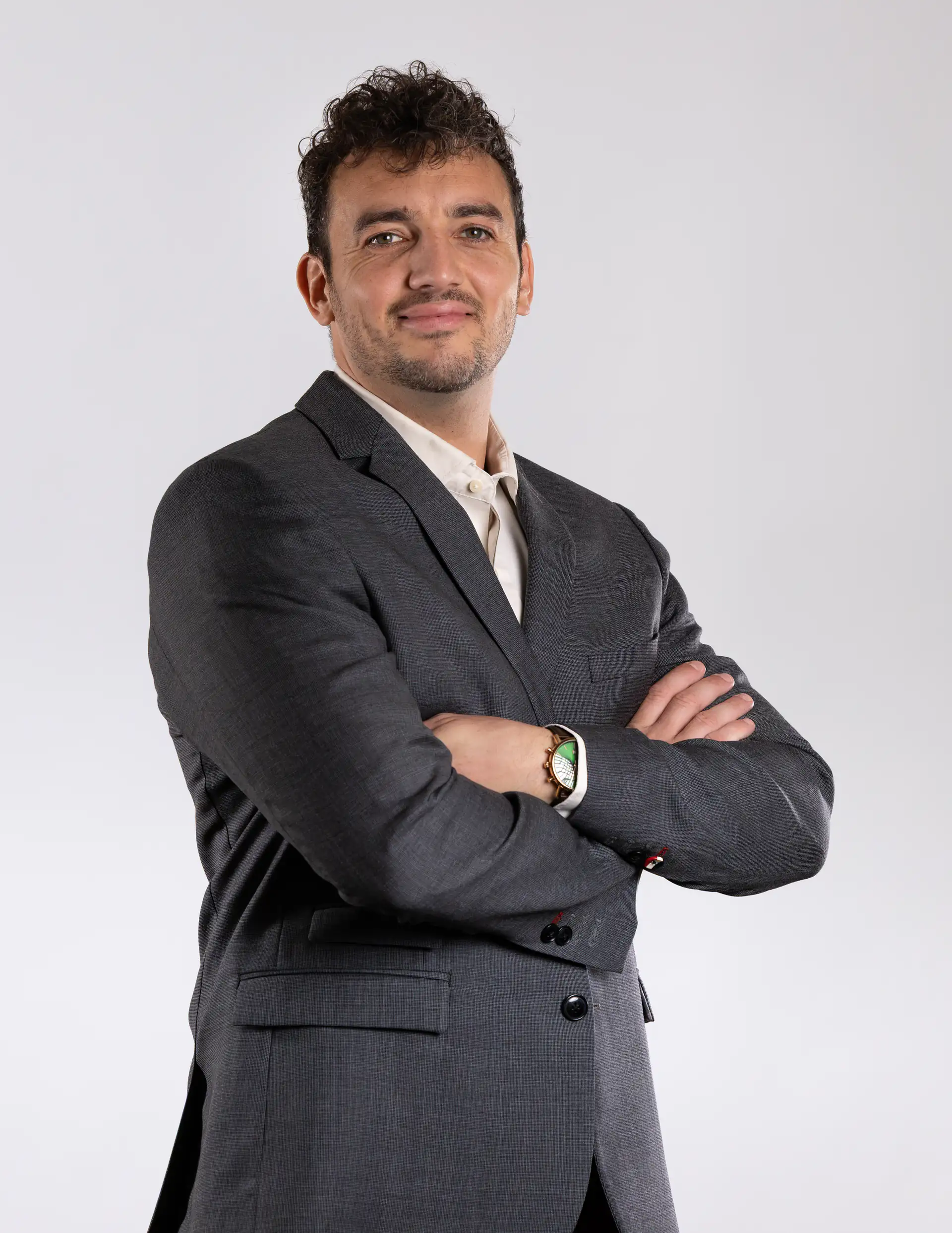 Théo Mével en costume sombre, les bras croisés, sur fond clair.